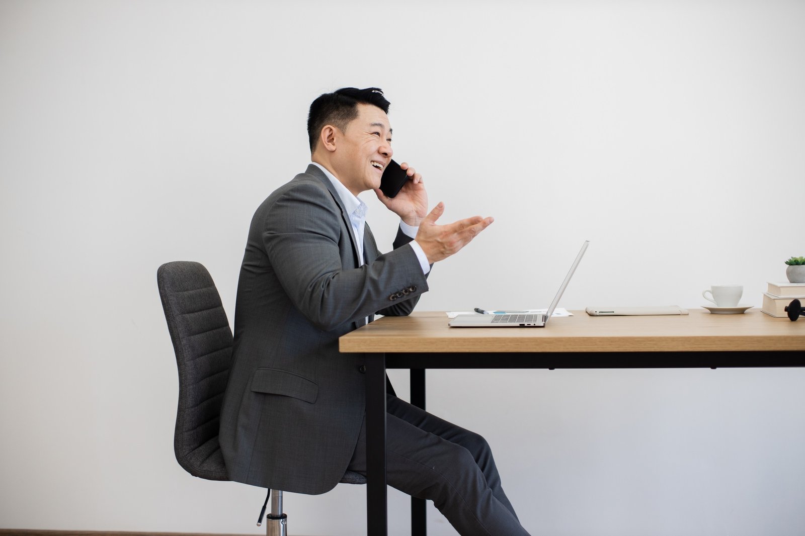 Asian businessman in office conducting call beside laptop